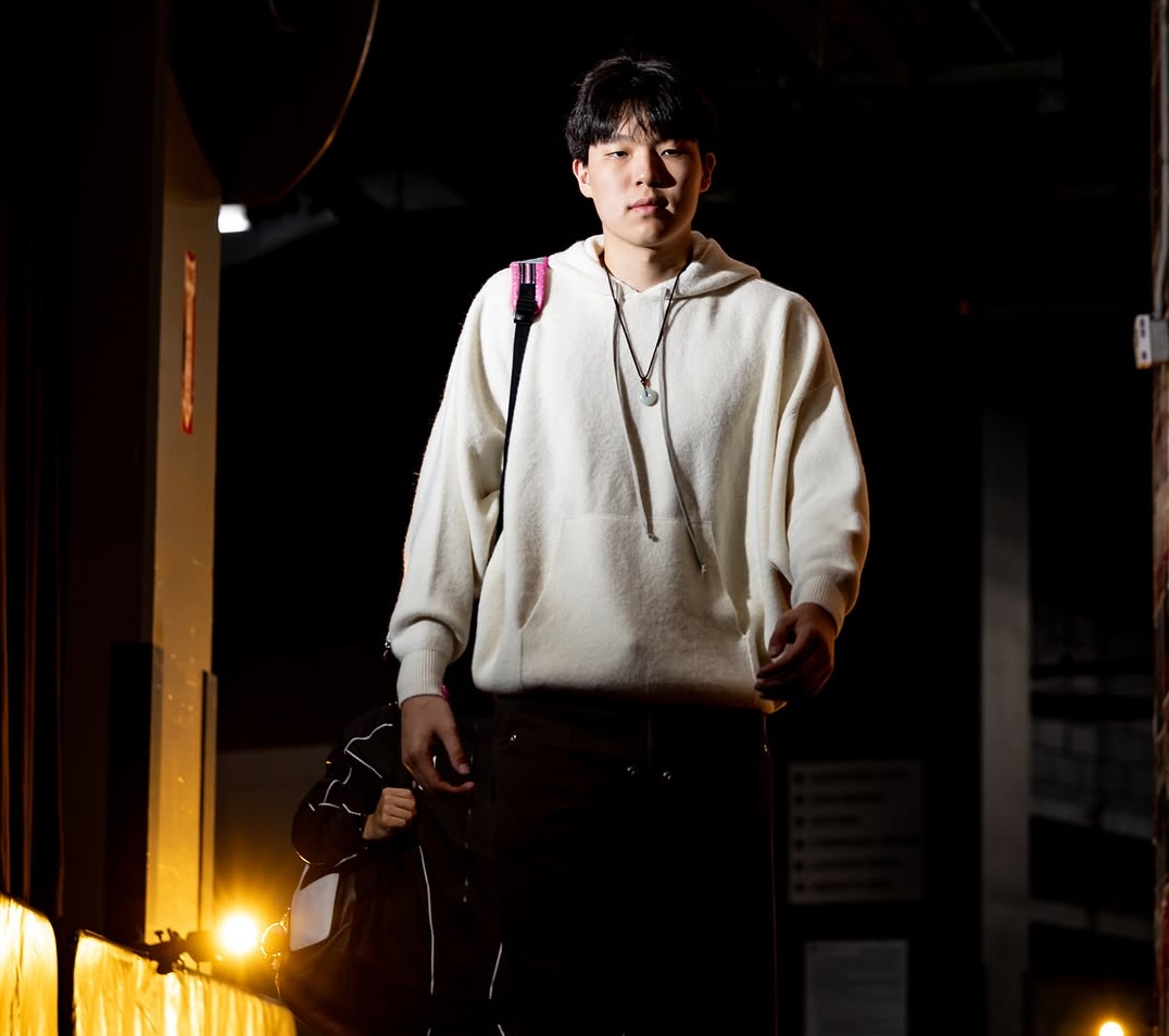 Las redes sociales de los Trail Blazers publicaron fotos de Yang Hansen entrando antes del juego: sudadera con capucha blanca y mochila rosa